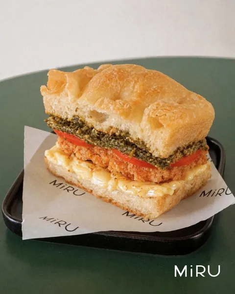 MiRU focaccia sandwich with pesto, tomato and cheese on MiRU-branded paper